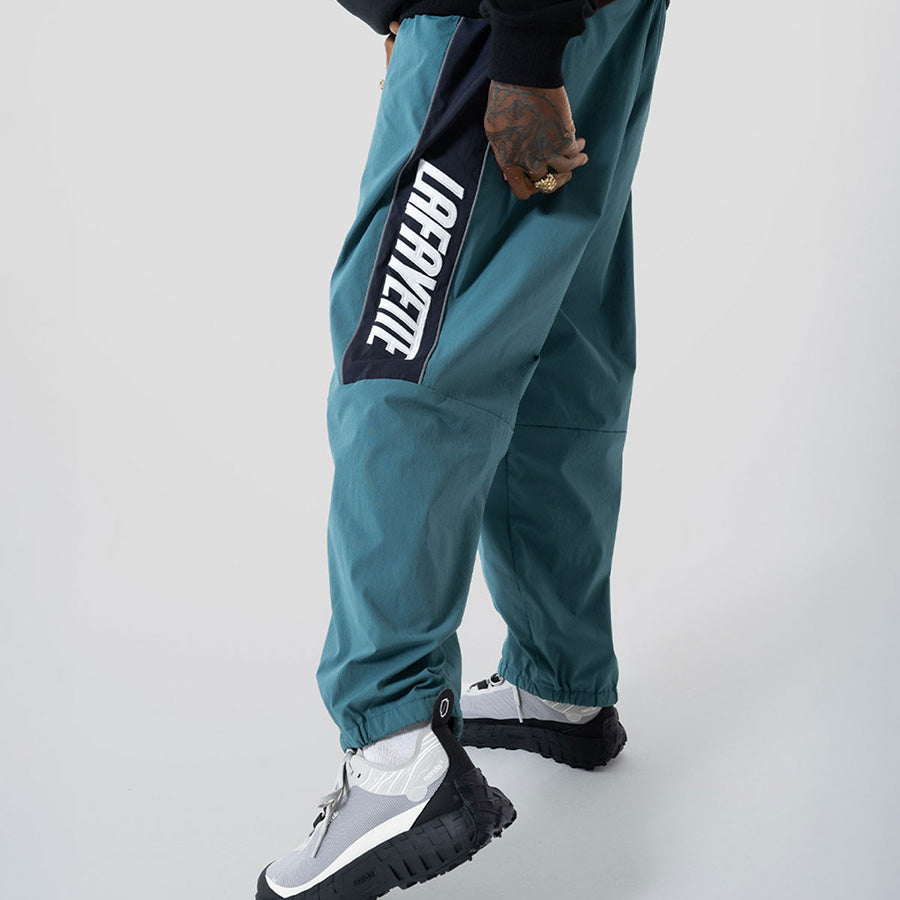 LFYT SPORTS LOGO TRACK PANTS トラックパンツ グリーン モデル着用 横向き 下半身 LA261202